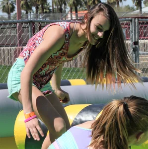 Brunette skinny teen in green shorts playing in a bounce house