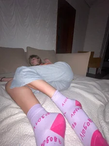 Young skinny girl wearing grey sweatpants and pink socks asleep on the couch