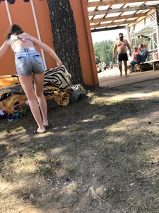 Young Skinny Girl Taking Off Her Denim Shorts Leaving a Swimsuit - Bending Over While Laying a Blanket on the Ground at a Lake Nature Park Gallery