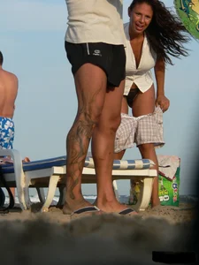 Topless tattooed lady on the beach with fake big tits