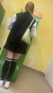 Cute girl wearing a dress and stockings using an ATM