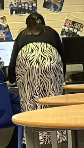 Teacher wearing a long zebra-patterned skirt bending over in class