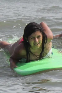 Brunette bikini girl on the beach and surfing in her bikini