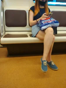 Girl in Mask and Shorts Sitting with Crossed Legs in the Subway Train