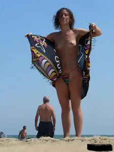 Topless beach milf looking sexy in a tiny g-string bikini