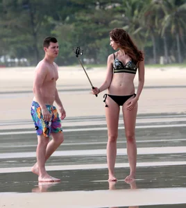 Babe in black bikini on the beach with her boyfriend
