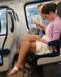 Girl in Sandals and a Dress Sitting With Crossed Legs in a Public Train Candid Photo