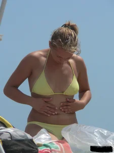 Sexy blonde on the beach in a yellow thong bikini