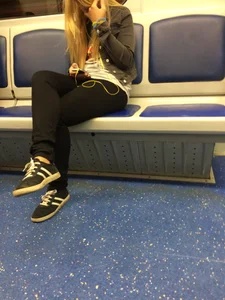 Girl in Tight Pants Sitting in a Subway Train with Her Legs Crossed Candid Photo