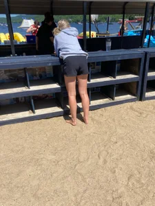 A Hot And Stocky Blonde Girl in Shorts Bend Over, Bare Feet on Sand