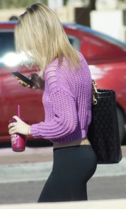 Beautiful skinny blonde in tight leggings and purple crop top showing sexy stomach