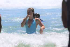 Blonde in blue thong swimsuit on the beach with friends