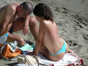 Topless brunette babe on the beach with an incredible bubble butt