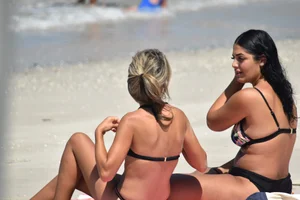 Blonde and brunette on the beach looking sexy in their bikinis