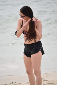 Brunette girl in black shorts and bikini top on the beach