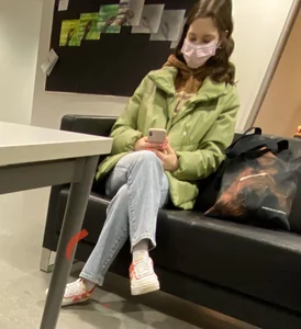 Feet of a Masked Girl in Sneakers Sitting With Crossed Legs