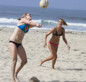 Hot girls playing beach volleyball in bikinis and shorts