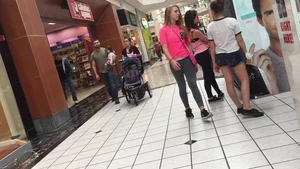 Little blonde teen in grey leggings at the mall with her friends
