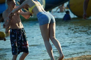 Hot Girl in Swimsuit Top and Denim Shorts by the Water on the Beach Creepshots