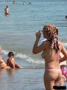 Topless tattooed lady at the beach with a nice ass in pink thong bikini