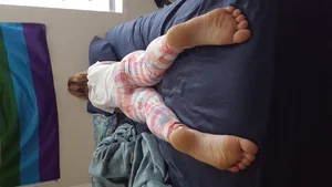 Girl in Cute Home Pants Lying on Her Tummy in Bed with Slightly Spread Legs - Bare Feet Closeup Creepshot
