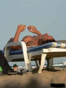 Topless tattooed lady on the beach with fake big tits