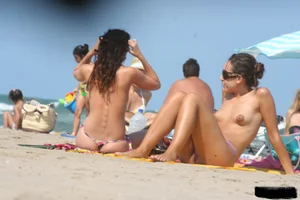2 topless girls at the beach in thongs