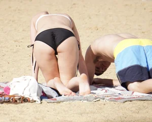 Sexy girl on the beach laying out and bending over in her bikini
