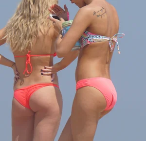 Two sexy girls in peach and pink bikinis on the beach