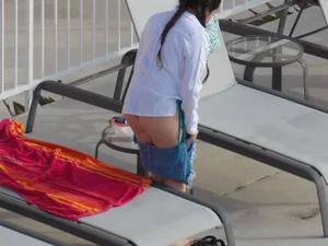 Sexy ass brunette sunbathing by the pool in thong bikini