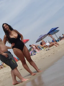 Thick brunette with huge boobs on the beach in black swimsuit