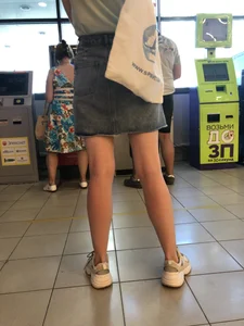 Young Candid Girl With Slim Pale Legs In a Denim Skirt Waiting in the Queue