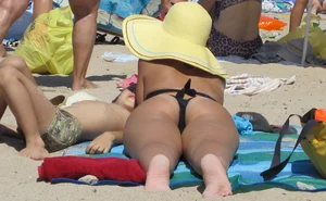 Candid Girl With a Hot Ass in a Swimsuit and a Hat Lying on a Beach
