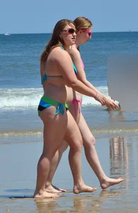Two beach friends in bikinis one with back dimples and the other thick