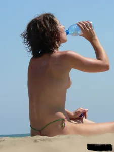 Topless beach milf looking sexy in a tiny g-string bikini
