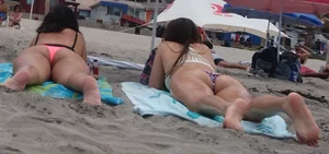 Pink and patterned bikini girls' asses laying on the beach