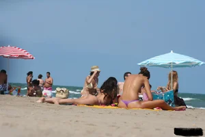 2 topless girls at the beach in thongs