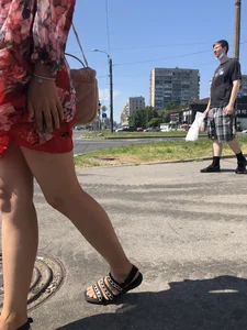 Hot street candid girl wearing a short dress and sandals standing on the crosswalk, wind is playing with her hair