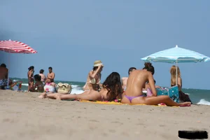 2 topless girls at the beach in thongs