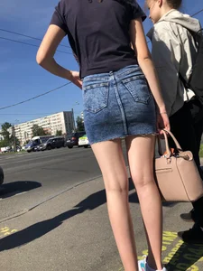 Cute Girl in a Short Denim Skirt Walking on a Street And Waiting on a Crosswalk Gallery