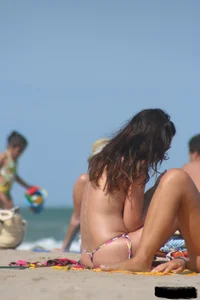 2 topless girls at the beach in thongs