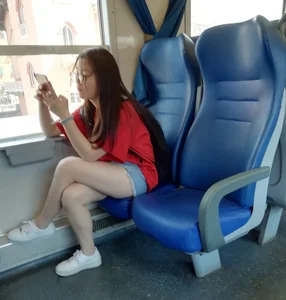 Two cute Asian teens on the bus in shorts showing their legs