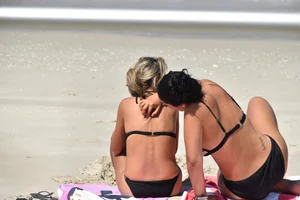 Blonde and brunette on the beach looking sexy in their bikinis