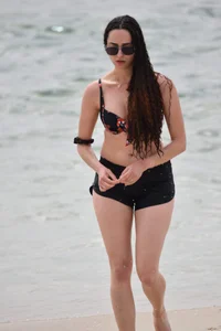 Brunette girl in black shorts and bikini top on the beach