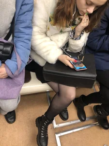 Very cute candid subway girl wearing black pantyhose sitting with crossed legs in the train