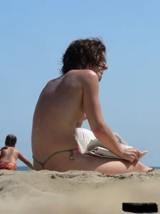 Topless beach milf looking sexy in a tiny g-string bikini