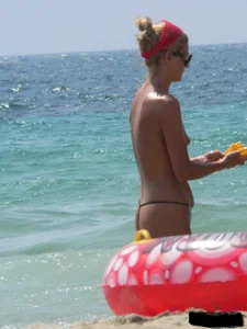 Topless skinny blonde lady in a g-string bikini at the beach