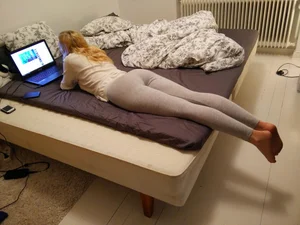 Hot candid barefoot milf in grey leggings lying on bed with her laptop, long skinny legs