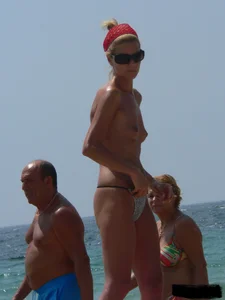 Topless skinny blonde lady in a g-string bikini at the beach