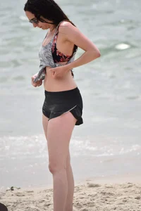 Brunette girl in black shorts and bikini top on the beach